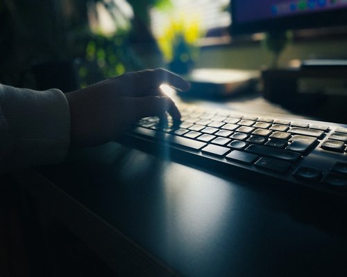 Close up of hands on keyboard with soft desk lamp illuminating the workspace